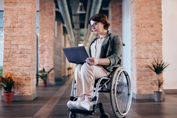 Woman with glasses & brown hair in wheelchair using a laptop
