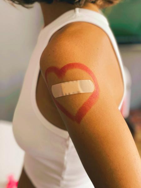 Close up of an arm with a vaccine bandaid, with a heart drawn around it