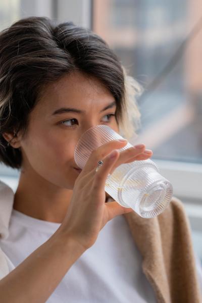 Young person drinking water while looking out a window