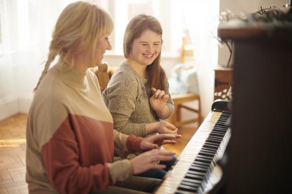 girl and woman sitting at piano, smiling