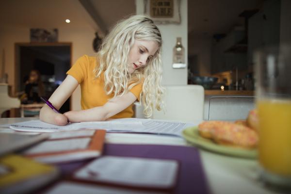 Blonde girl who is an amputee writing at a table