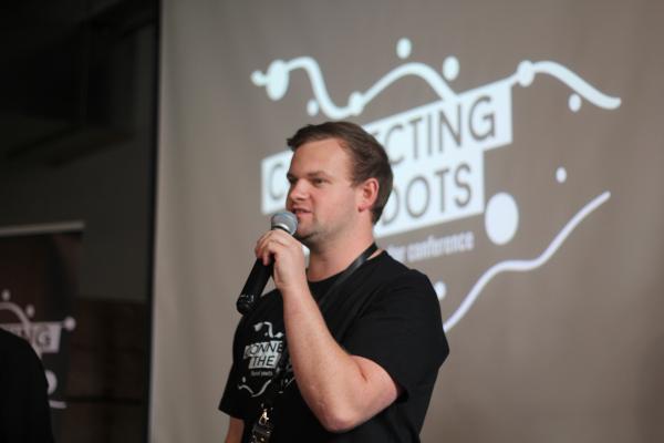 image of Josh Baker holding a mic at Connecting the Dots conference