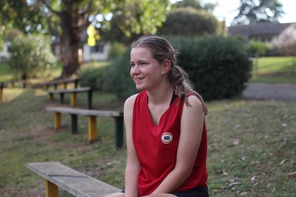 A young person in a sports singlet smiling