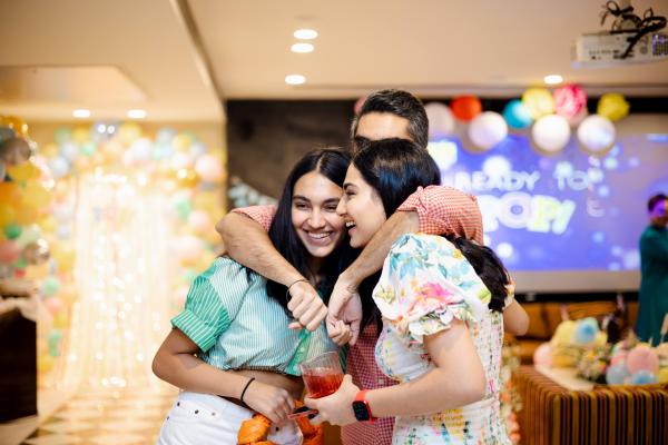 Three people embrace at a party