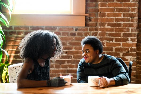 two dark skinned women sitting in a cafe
