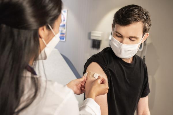 Nurse putting a bandaid on a young person's upper arm