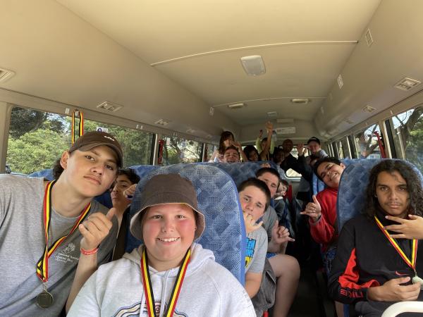 Young Aboriginal people smiling and wearing medals on a bus