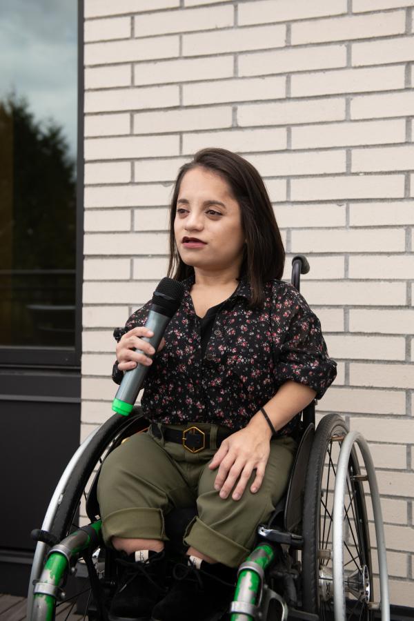 A young wheelchair user speaking into a microphone