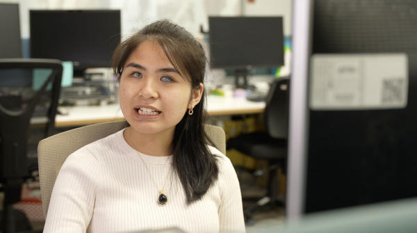 An image of Anna Dang smiling at the camera in an office setting.