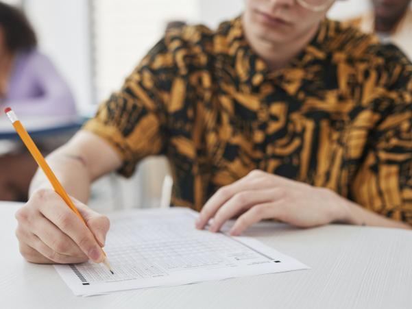 A close-up of a person with a colourful shirt doing an exam in a classroom