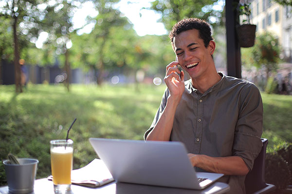 Young person smiling on phone and laptop